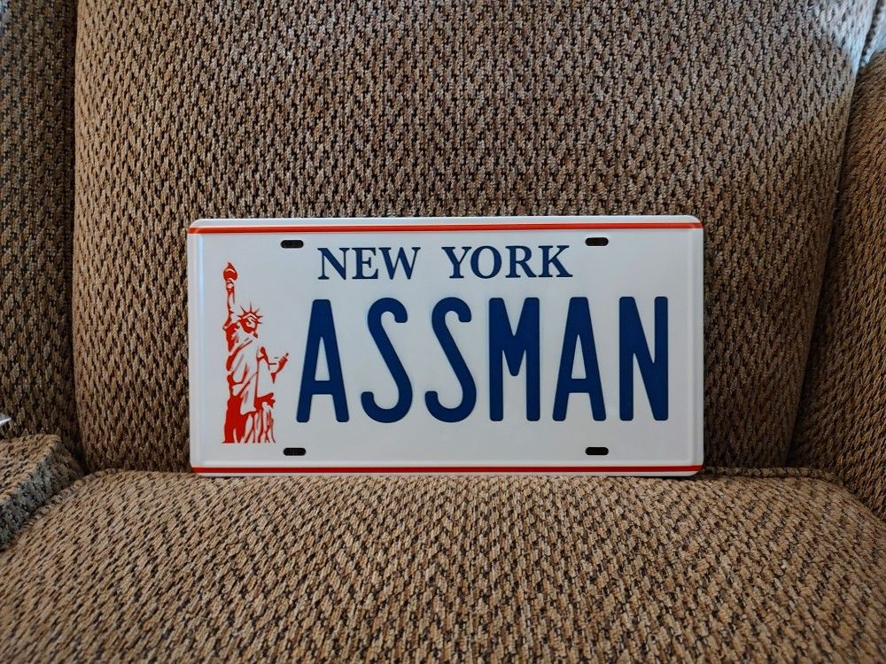 SEINFELD ASSMAN METAL LICENSE PLATE. 12" X 6". NEW. PICKUP ONLY.