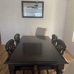 Brown wood dining table 6 chairs with mirrors and wall portraits