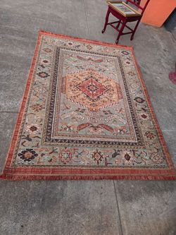 This rug is a Persian-style model from Threshold featuring a floral pattern in rust and teal.