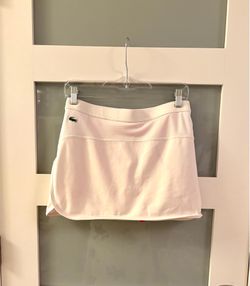 The white Lacoste golf skirt features Ultra Dry moisture-wicking technology and a built-in lining.