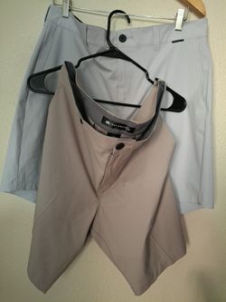Two TravisMathew men’s shorts in taupe and light gray.”