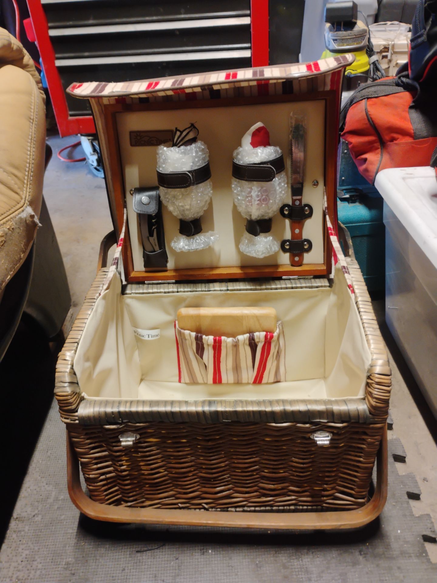 Picnic Time Kabrio wicker picnic basket featuring a striped fabric lid and a built-in wooden tabletop.