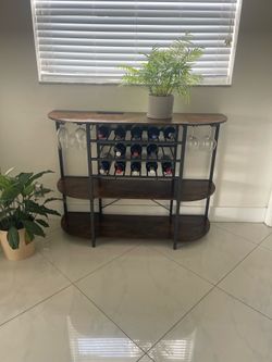 Dark wood versatile wine cabinet with decorative shelves, wine bottle and wine glass storage and electrical outlet