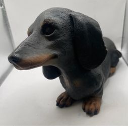 A novelty black and tan Dachshund dog candle, complete with a fabric wick protruding from its back.