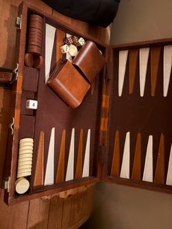 This is a portable backgammon set with a leatherette (faux leather) carrying case. It appears to include:  * ✔️ Folding backgammon board * ✔️ Two dice