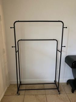 a double-rod garment rack on wheels in black.