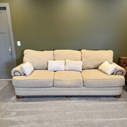 Large, comfortable beige sofa with rolled arms and nailhead trim. Clean, well cared for, very cozy.