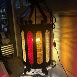 Very large and vintage wrought iron chandelier with hanging chain and switch in excellent condition. Has three colors of glass with no chips, brakes o