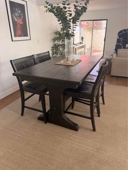 rustic dark wood dining set featuring a solid trestle table paired with a matching bench and slat-back chairs.