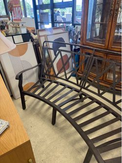 curved, black metal garden bench features a lattice-work back design and slatted seating.