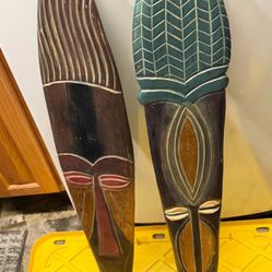 These items are decorative hand-carved wooden wall masks in a tribal style, often sold as souvenirs or home decor. 