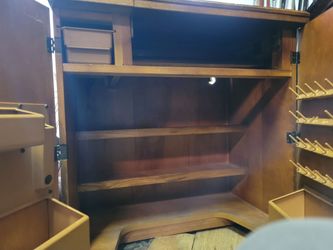 vintage 1970s rolling wooden sewing machine cabinet, featuring a fold-out top surface, two faux-top drawers, and cabinet doors with ornate geometric p