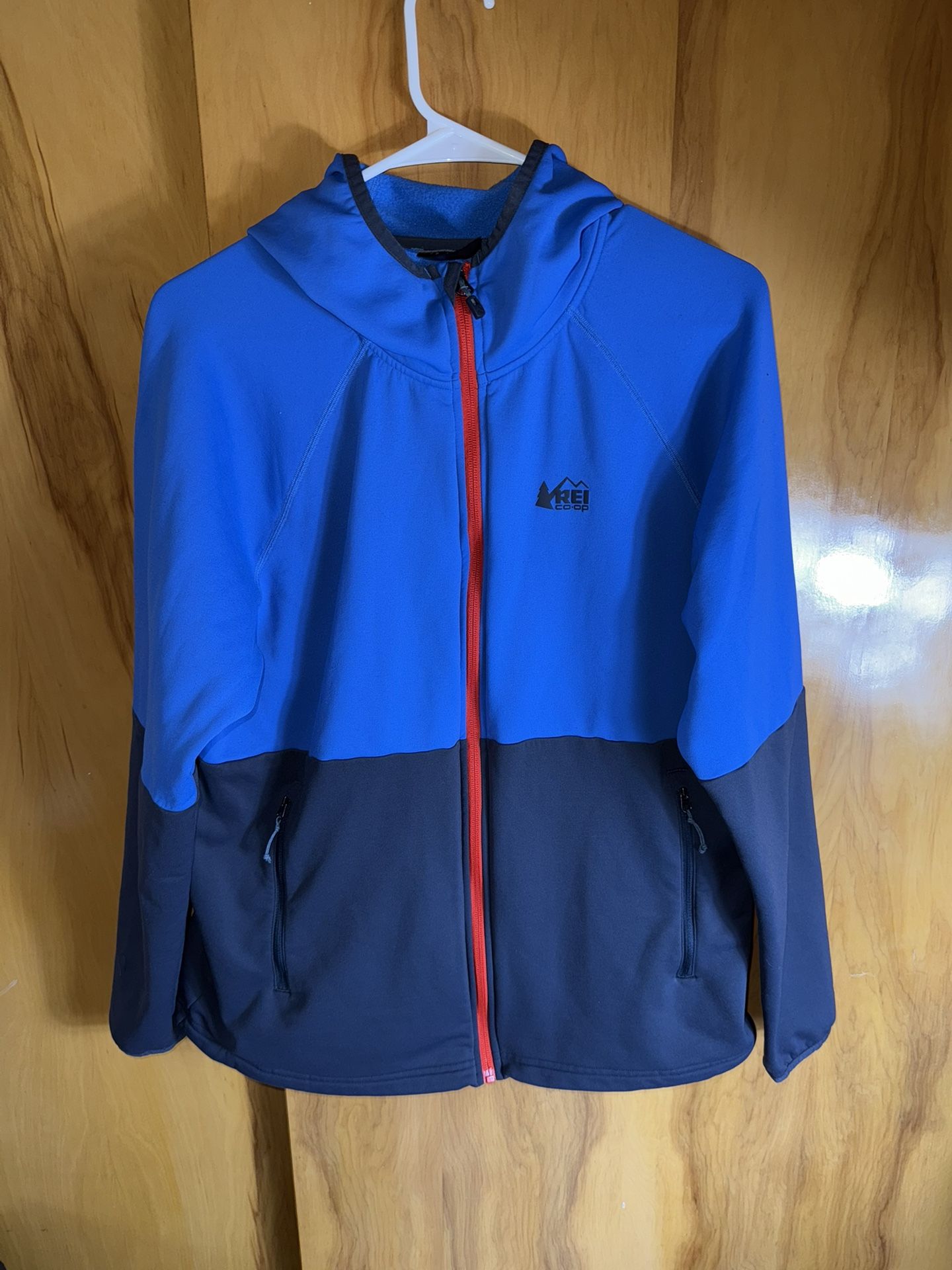 REI Co-op Flash Hyperstretch fleece jacket in a blue and black colorblock design with an orange zipper