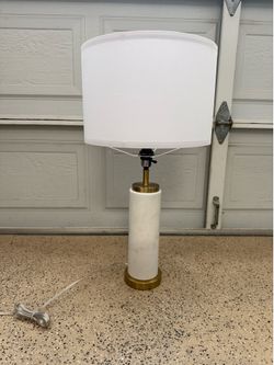 West Elm table lamp with a white faux marble base with brass accents and a white linen drum shade.