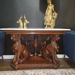 antique Egyptian Revival-style mahogany console table featuring hand-carved sphinx figures as the base and a marble top. 