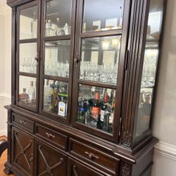 Elegant solid wood china cabinet.  Features:  • Three glass display sections with glass shelves and interior lighting  • Mirrored back panels that hig