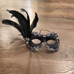 black Venetian-style masquerade eye mask accented with dark feathers, silver-toned sequins, and floral rhinestone embellishments, great condition