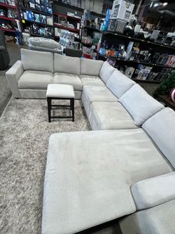 U-shaped light colored fabric couch from Costco with chaise and storage