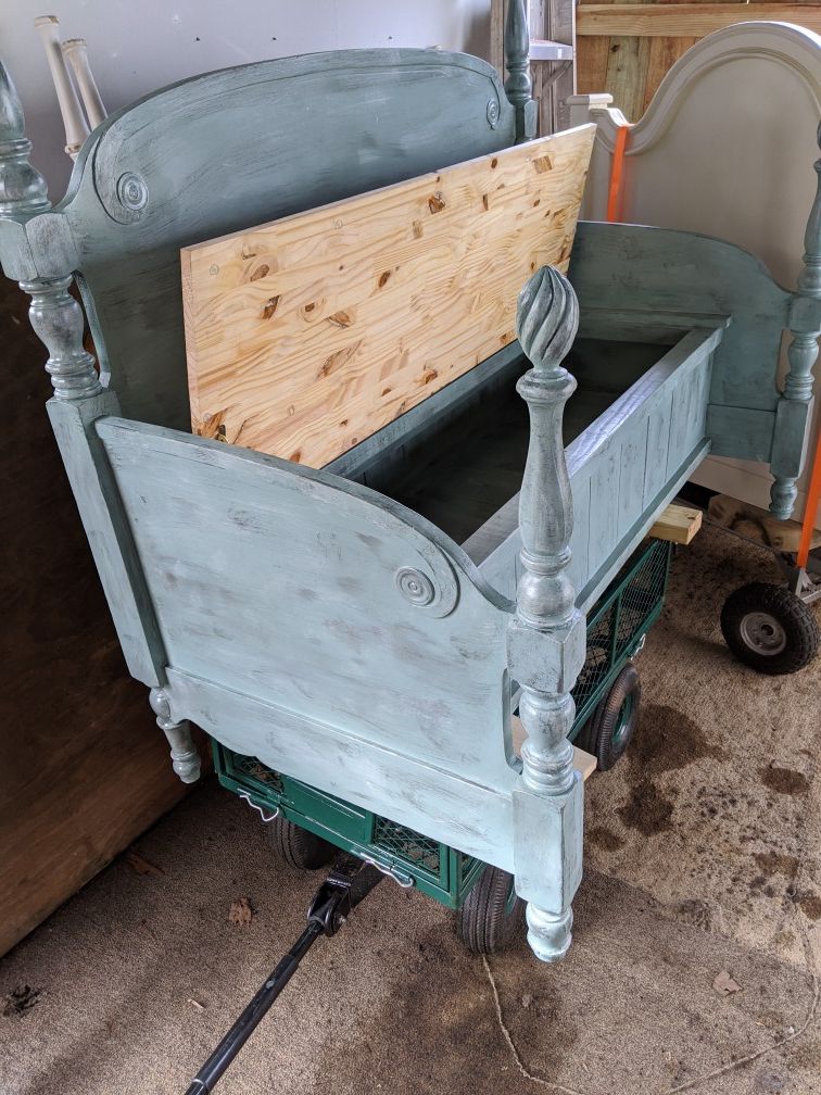 A bench made out of a old bed frame with storage in it