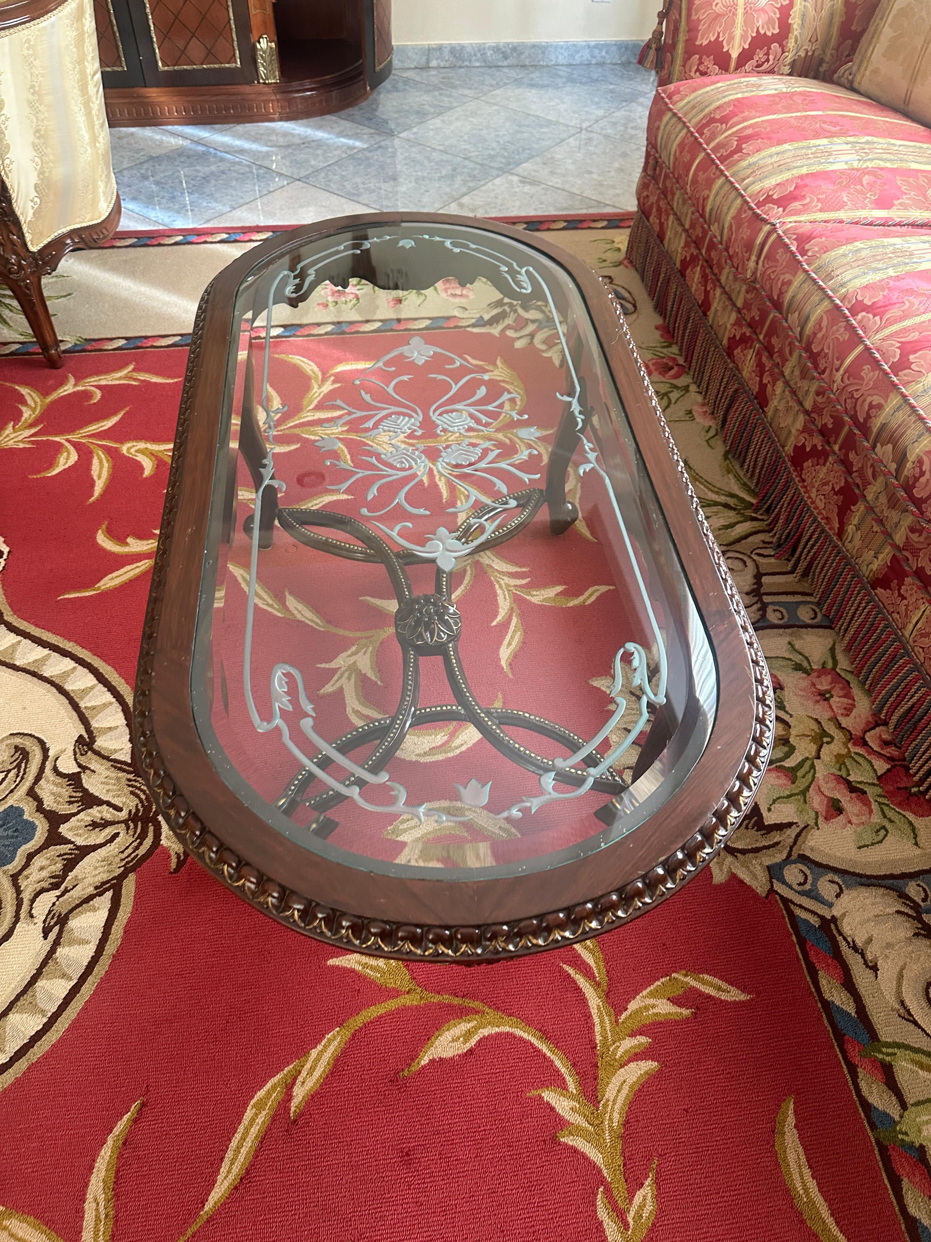 Vintage dark wood coffee table with a glass top and hand-carved detail