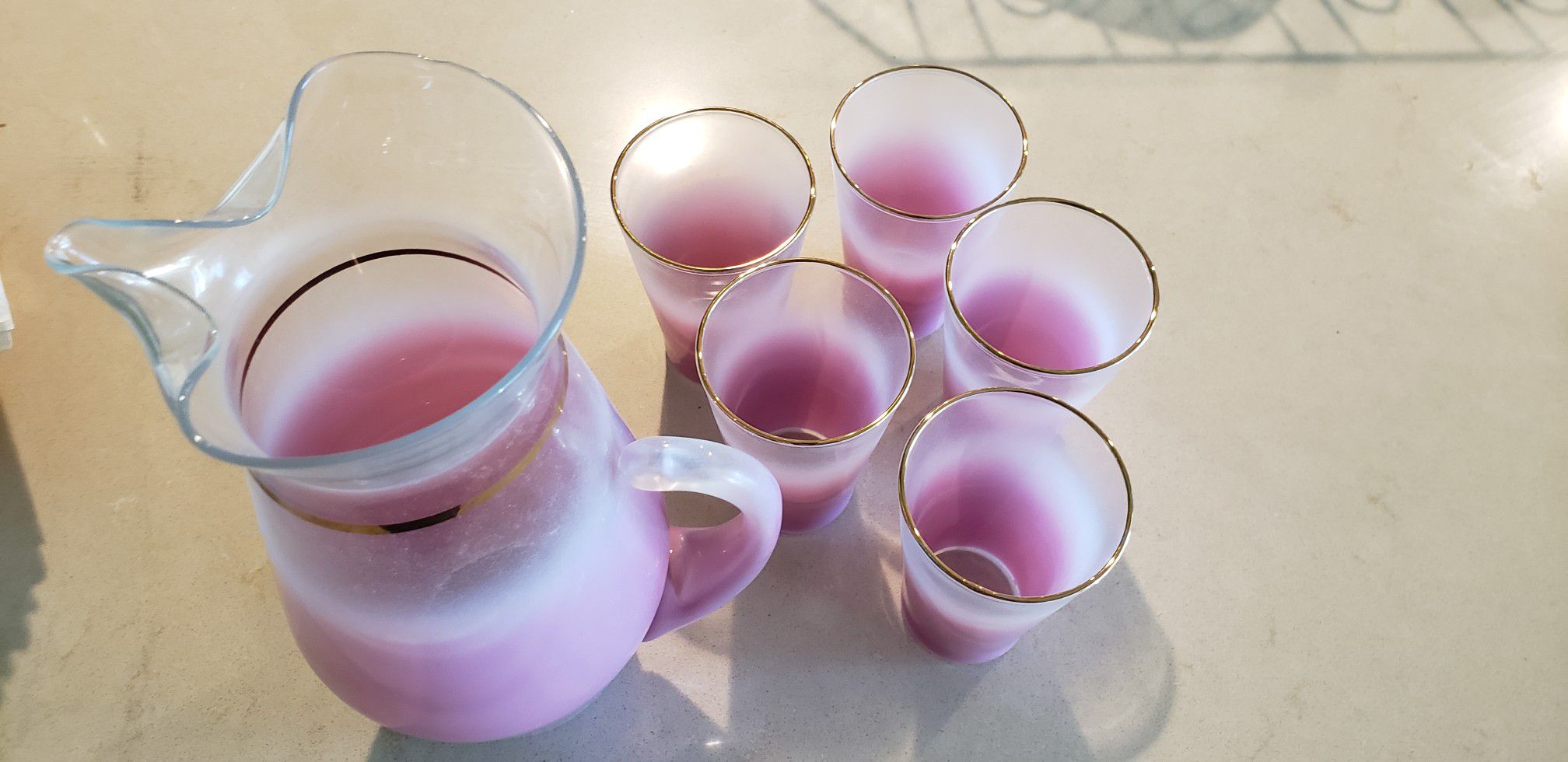 Glass Carafe with 5 matching glasses. Pink with gold trim.