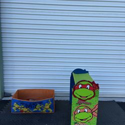 25"x24" Teenage Mutant Ninja Turtles (TMNT) toy shoe wood storage organizer.  The unit features a green and blue shelf with an orange fabric bin. The 