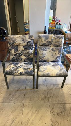 Pair of metal framed patio chairs with padded tie-down cushions