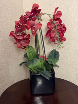 Artificial red orchid in black vase
