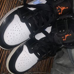 The grade school Jordan 1 Mid Black Racer Blue White (GS) features a black synthetic upper with white leather overlays in the center and forefoot.