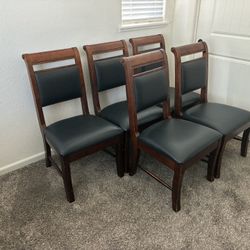 Set of 5 matching dining chairs featuring solid wood frames and cushioned black faux leather seats and backs. Clean, elegant design that works with ma