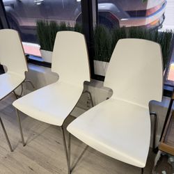  3 modern white chairs with metal legs. 