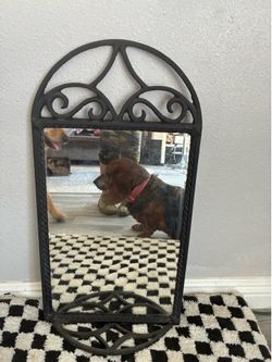 Black wrought iron mirror with small shelf attached.
