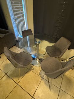 Glass modern table with 4 grey chairs. 3’8” wide
