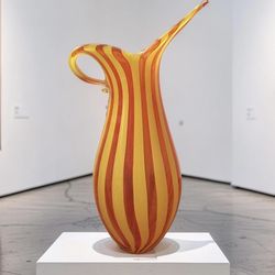 A vintage Murano glass pitcher with yellow and orange stripes.