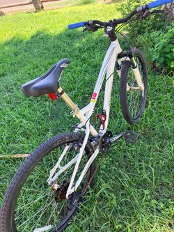 This is a white Specialized Myka women's mountain bike featuring a patterned frame design and a blue handlebar grip.