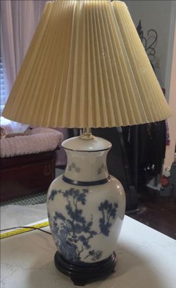 blue and white porcelain ginger jar table lamp with a pleated cream lampshade and a dark wood base.