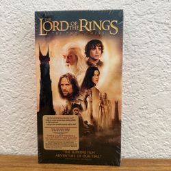 Official cover art for The Lord of the Rings: The Two Towers. Includes prominent gold and brown tones. Iconic title text visible. Great for collectors