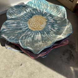 These are handmade, flower-shaped ceramic or stoneware bowls/dishes, 