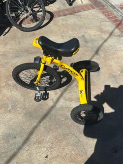 Yellow Cyco Cycle folding tricycle has a steel frame and three wheels. This stunt bike is equipped with a black padded seat and textured pedals. The f
