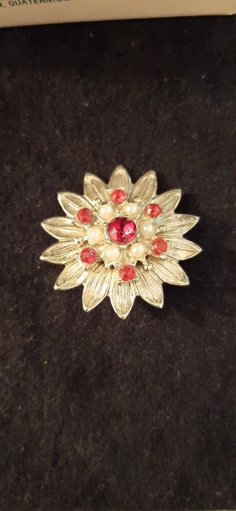 Gold tone brooch with red stones and pearl accents.