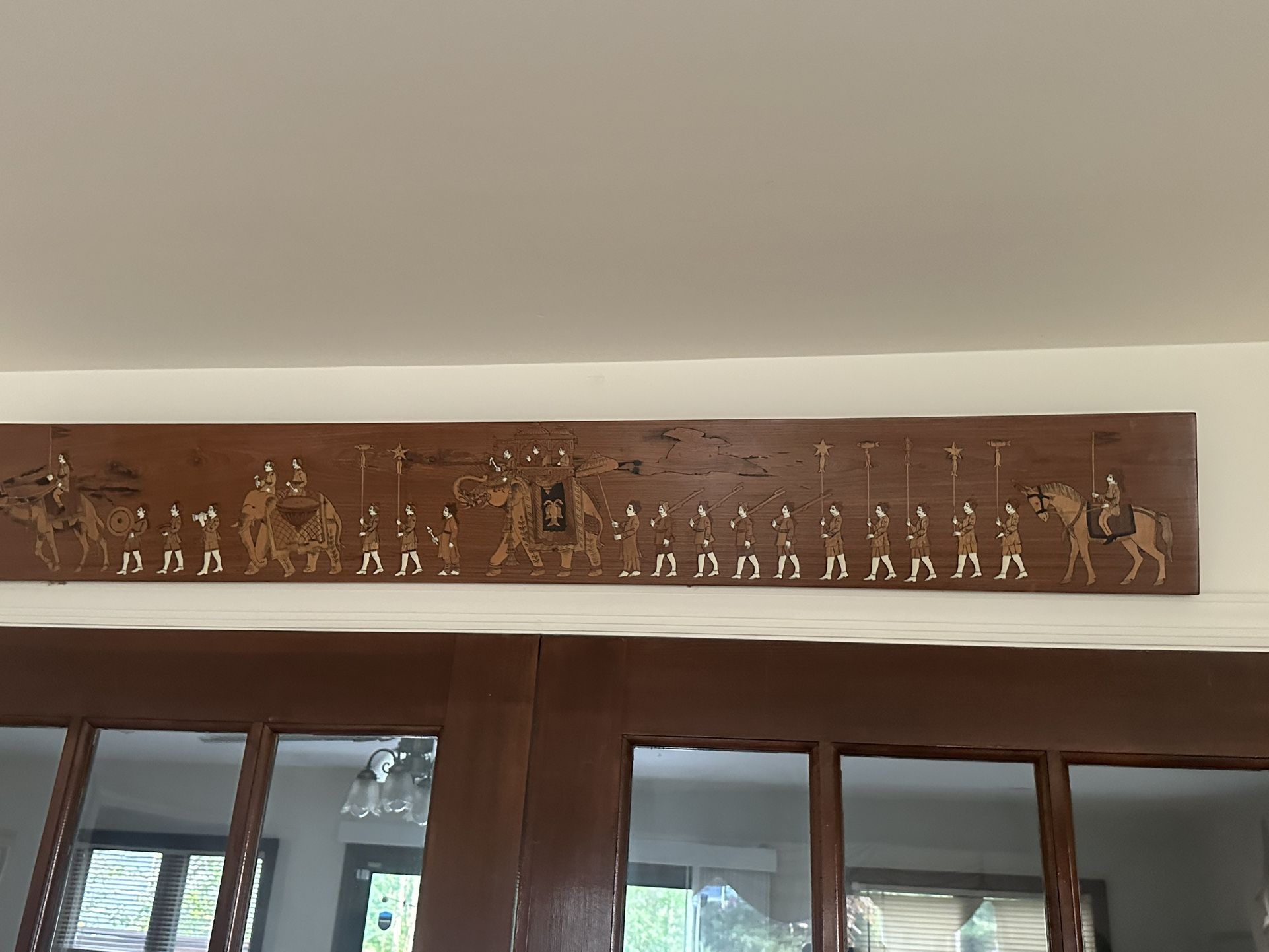 Decorative wooden panel featuring a detailed procession scene. 4’ x 6”