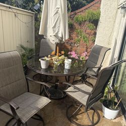 Patio Furniture Set - Outdoor table with umbrella and four chairs.