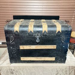 antique steamer trunk with a black metal exterior and wooden slats