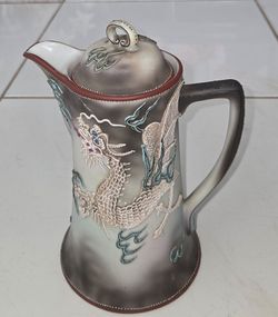 Vintage Japanese moriage raised‑dragon lidded coffee pot. Embossed dragon and cloud motifs, gradient smoky finish, red‑trimmed rim. Measures 10 inches