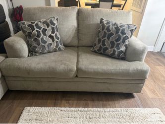 Matching Ashley sofa and loveseat. Grey color with six couch pillows.