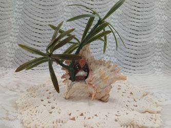 Vintage seashell art with plastic plants and ceramic monk figurine