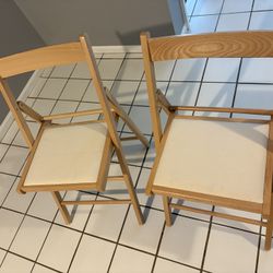 Two Wood and cream fabric folding chairs