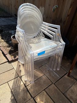 acrylic/polycarbonate oval-back armchairs styled after the iconic Philippe Starck "Louis Ghost" chair for Kartell.