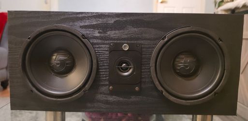 Black woodgrain wrap center channel speaker modified with a polkaudio  banana plug terminal with crossover inside it.