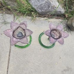 Pair of hand-blown Murarno-style purple flower glass candle holders with green curly stems.